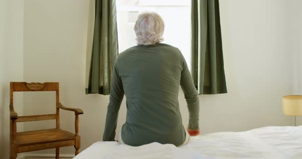 Senior man sitting on bed in bedroom at home 4k