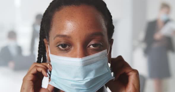 Afro Young Businesswoman Wearing Protective Mask Standing in Modern Office and Looking at Camera
