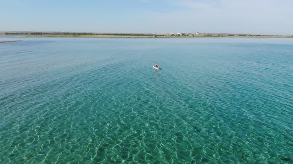 A Young Woman on a Paddleboard is Exercising in the Morning