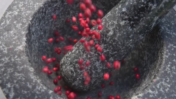 Closeup of Spicy Rose Peppercorns Falling and Bouncing in a Grey Stone Mortar