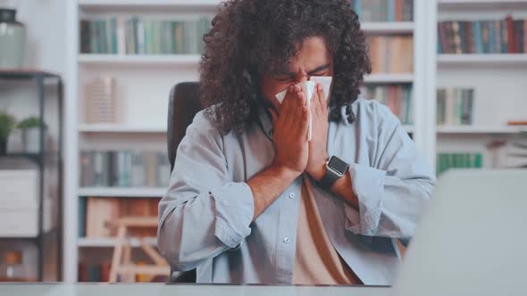 Young Unhealthy Arabian Man Sneezes Covering Mouth with Paper Tissue