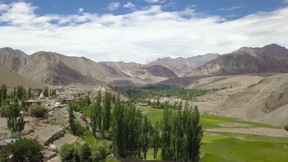 Establishing Aerial of Himalayan Mountain landscape in Ladakh, India. Green farm land below