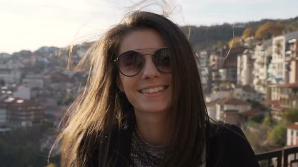 Beautiful Smiling Cheerful Girl Posing, Wearing Sunglasses and Shined By the Sunset