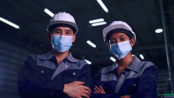 team of engineers wearing medical face masks working together in factory under COVID-19 situation