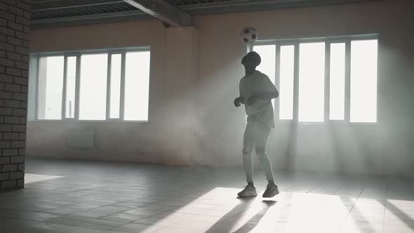 Black Man Football Soccer Player Practicing Tricks Kicks and Moves with Ball Inside Empty Covered