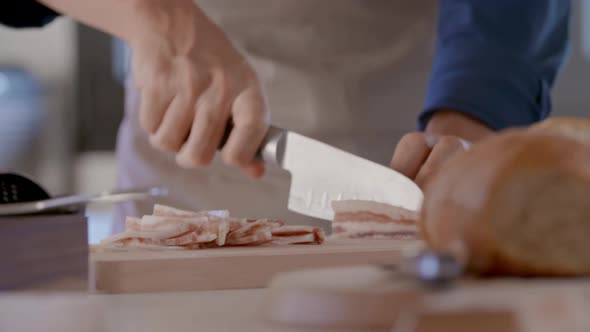 Detail of Man Hand Cutting Jowl Bacon with Knife