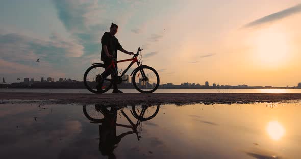 Silhouette of Bicyclist Sit Down Into His Bike at Sunset Slow Motion