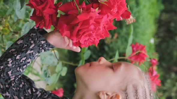 Little Girl Smells Fragrant Rosebush Outdoors