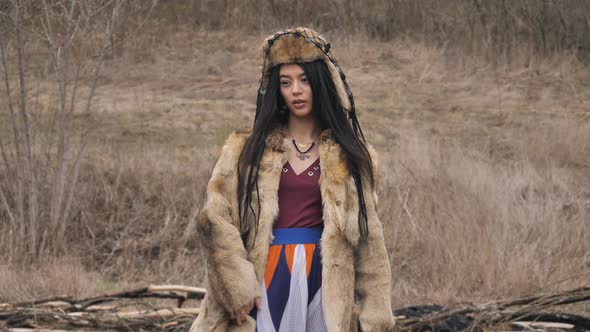 asian young woman in ethnic clothes posing looking at the camera in the steppe at nature. slow mo