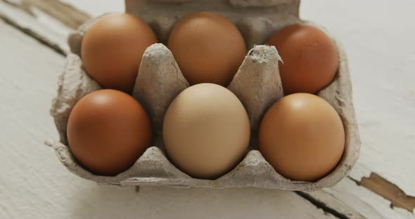 Video of overhead view of brown eggs in egg carton on rustic background