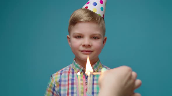 Female Hand Lighting Birthday Cake Candles for Preschool Boy Wearing Party Hat