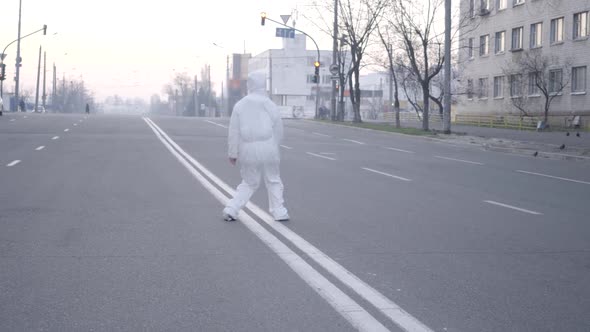 Wide Shot of Positive Caucasian Woman in Antiviral Suit Jumping on Empty City Road During Covid-19