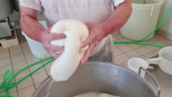 Cheesemaker making  stretched curd  to produce mozzarella and caciocavallo in cheese factory