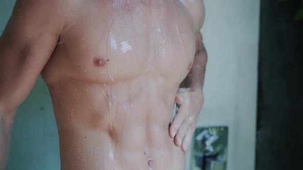 Close Up of Naked Muscular Torso of Man Taking Shower in Bathroom Slow Motion