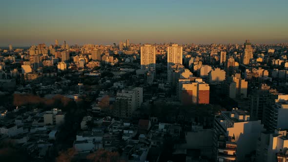 Drone: Sunset over the city. Golden Hour over buildings and towers. Foward Movement. Slow.