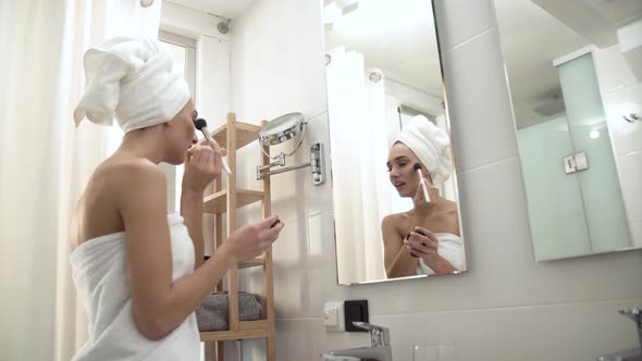 Makeup. Woman Applying Powder On Face Skin At Bathroom