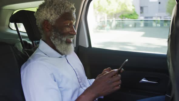 African american senior man using smartphone while sitting in the car