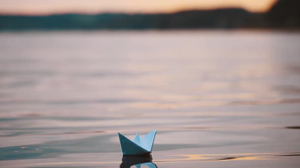 Blue homemade boat on water on blurred evening background.