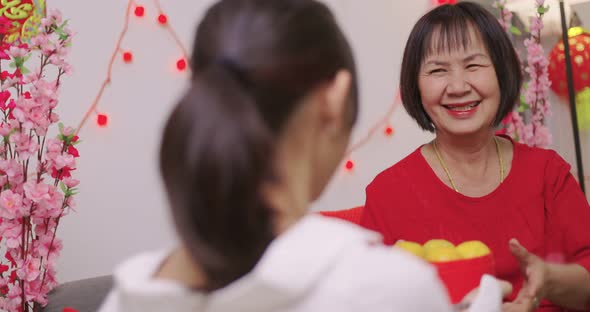 Happy Asian Girl Giving Her Grandmother Orange for Chinese New Year Blessing Gift.