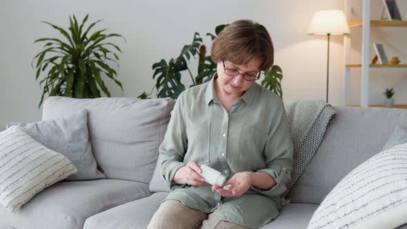 Senior Adult Woman Holding Painkiller Pills on Female Hand Pouring Capsules From Medical Bottle