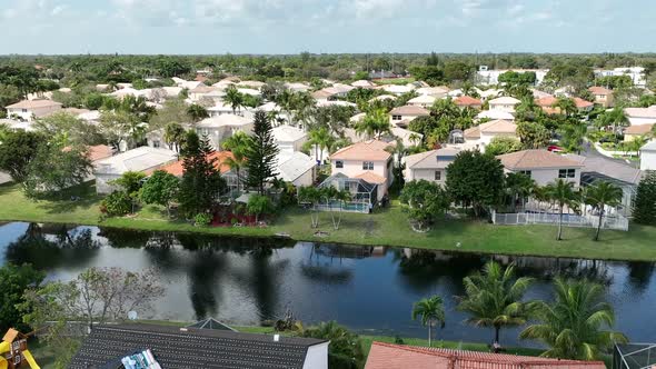 An aerial shot over a residential neighborhood in Florida on a sunny day with a dark, deep canal. Th