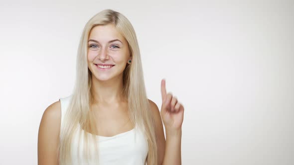 Cute Young Girl with Long Hair Gesturing with Index Finger Side Showing Smiling Isolated on White