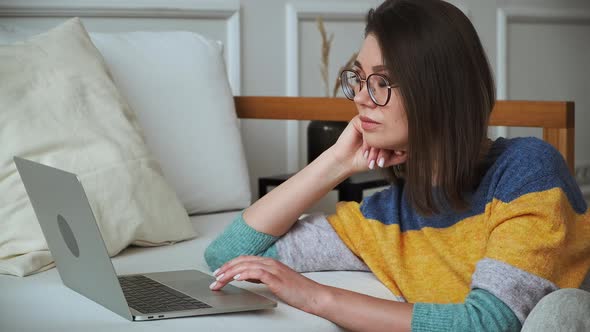 Young Woman Using Laptop Using Touchpad Sitting on the Floor Near the Sofa at Home Remote Work Work