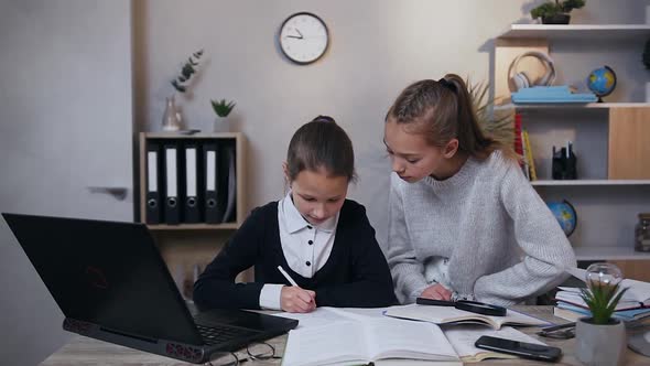 Girl Giving High Five to Her Younger Sister while Doing Together Hometask at Home