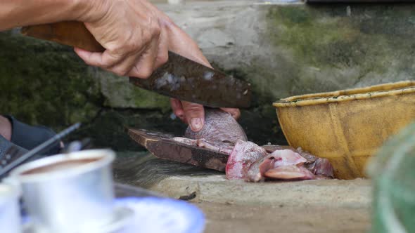 Close Up View on Hands Slicing Fish on a Wooden Board in the Dirty Outdoor Kitchen.