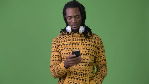 Young Handsome African Man with Dreadlocks Against Green Background