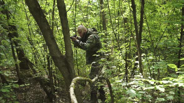 View of Taking Aim in Overgrown Forest of Fighter in Camouflage with Gun