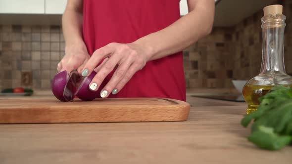 A Woman in the Kitchen Cuts a Red Onion with a Knife Slow Motion