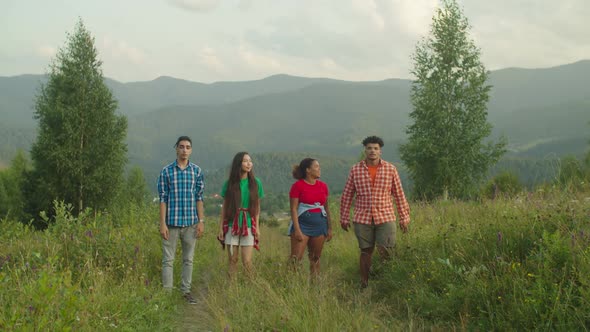 Cheerful Diverse Multiethnic Hikers Jumping on Mountain Peak at Sunset