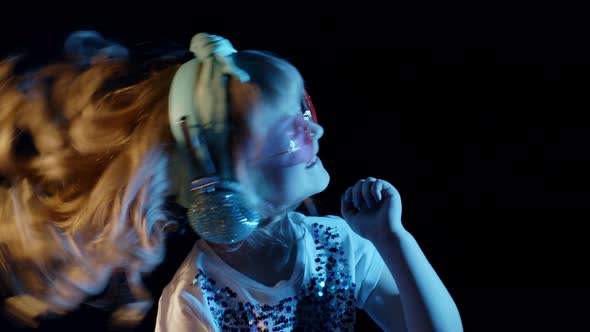 Futuristic Hipster Teen Girl Listening Music in Headphones Dancing in Neon Lights at Disco Club