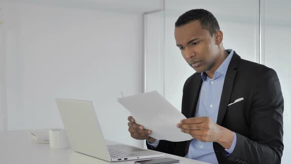 Upset Casual AfroAmerican Businessman Reacting to Fail Contract Report Reading