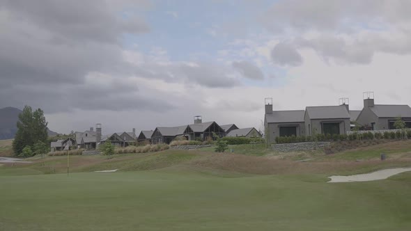 Golf field with a flag on the distance and buildings. Filmed on gimbal. Slow motion