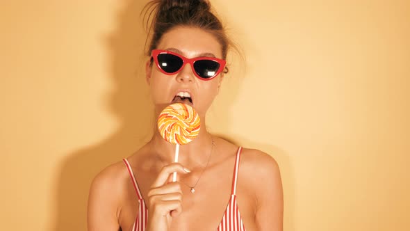 Closeup portrait of sexy girl eating lollipop. Woman licking candy in sunglasses