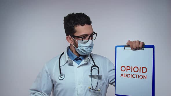 Male Doctor is Holding a Picture with the Inscription Opioid Addiction