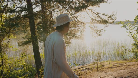 Young Man Walks on Hilly River Bank and Smiles Looking Ahead