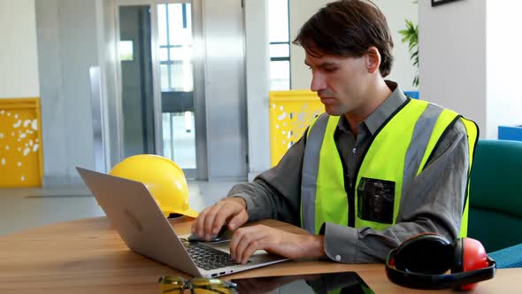 Male worker using laptop and digital tablet at desk