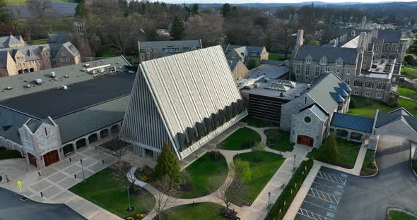 American flag at large campus with church and buildings. Gothic stone architecture.