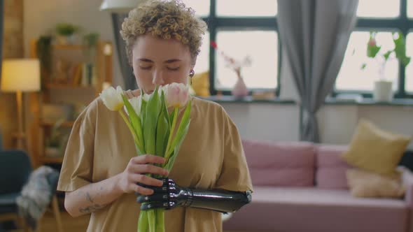 Girl with Prosthetic Arm Smelling Fresh Tulips at Home