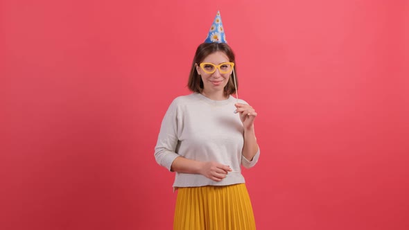 Happy Young Woman in Party Hat Holding Birthday Accessories on Red Background.