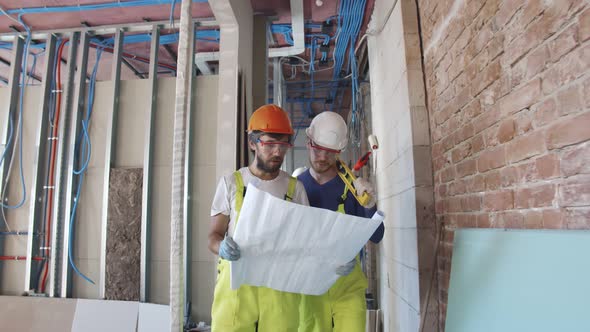 Construction Workers Study Architectural Blueprint on Work Site
