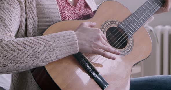 Young woman at home learning to play the guitar