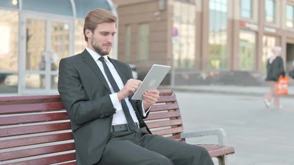 Businessman Using Tablet While Sitting Outdoor on Bench