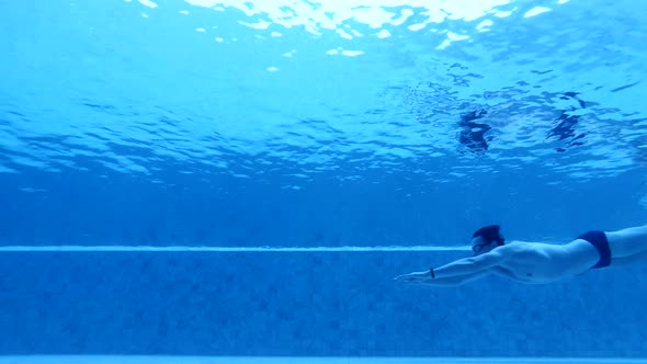 Man in Swimsuit and Goggles Moves Under Water Breaststroke Style