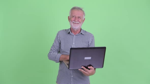 Happy Senior Bearded Man Thinking While Using Laptop