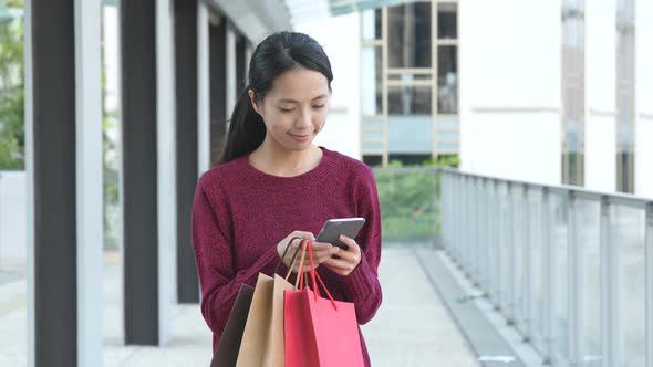 Shopping woman holding paper and using mobile phone 