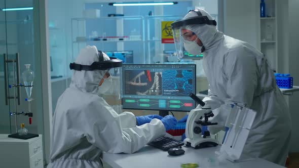 Chemist in Ppe Suit Working at Pc While Lab Technician Bringing Her Blood Samples